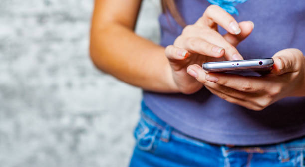 ung tonåring flicka hand med mobiltelefon eller smartphone på grå vägg bakgrund - closeup finger bildbanksfoton och bilder
