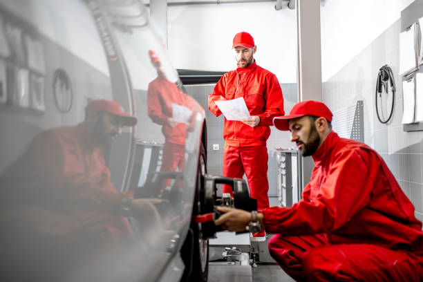 Auto mechanics making wheel alignment at the car service Handsome auto mechanic in red uniform fixing disk for wheel alignment at the car service wheel cap stock pictures, royalty-free photos & images