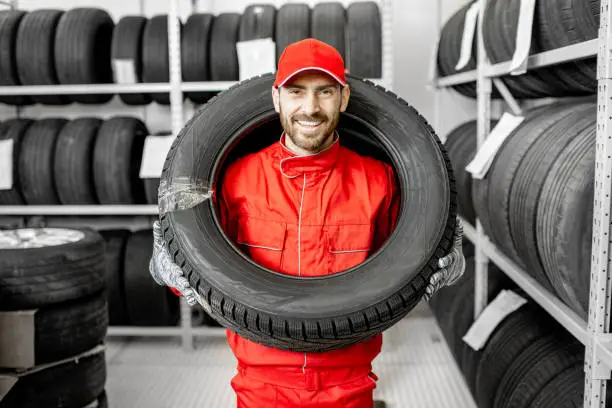 Photo of Worker wearing car tire in the storage