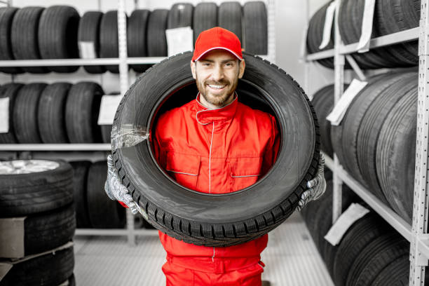 pracownik noszący oponę samochodową w schowku - vehicle part warehouse storage room repairing zdjęcia i obrazy z banku zdjęć