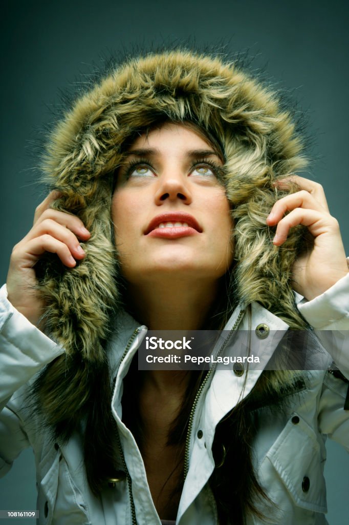 Giovane donna con cappotto invernale con cappuccio in pelliccia - Foto stock royalty-free di Moda