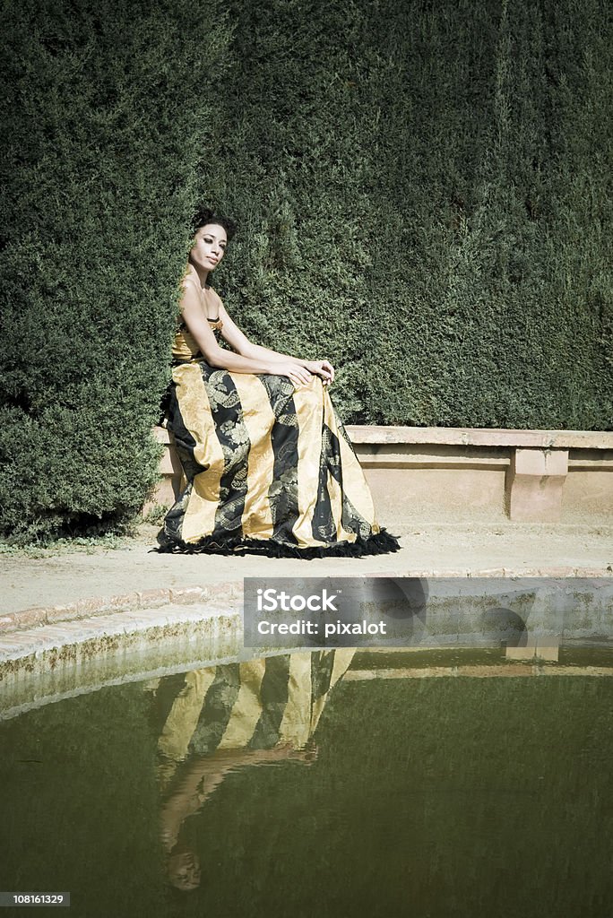 Mujer sentada en el borde del estanque del jardín - Foto de stock de Lujo libre de derechos