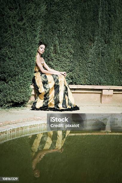 Mujer Sentada En El Borde Del Estanque Del Jardín Foto de stock y más banco de imágenes de Lujo - Lujo, Modelo de modas, Sentado