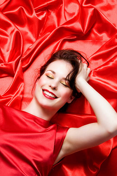 Young Woman Lying on Red Sheets stock photo
