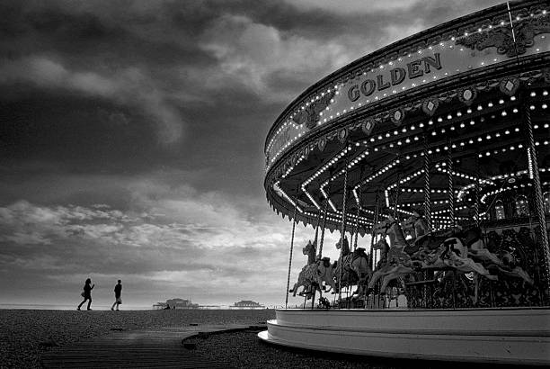 Vintage Carousel and People Walking on Brighton Beach  brighton england stock pictures, royalty-free photos & images