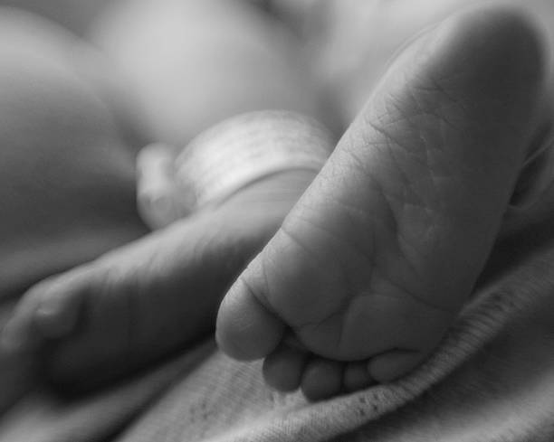 Close-up of Newborn Baby's Feet with Hospital Bracelet on Ankle  baby bracelet stock pictures, royalty-free photos & images