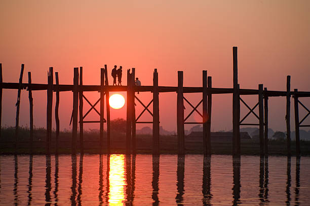 Myanmar: Crossing U Bein Teak Bridge at Sunset  u bein bridge stock pictures, royalty-free photos & images