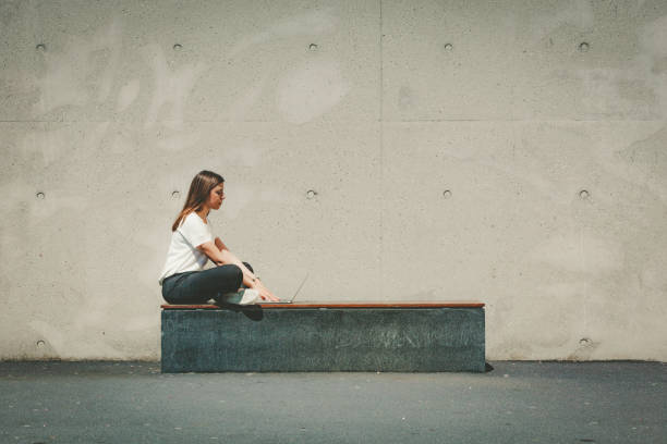 istock young woman sitting on a bench while working on laptop 1081625456