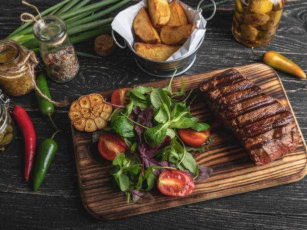istock Grilled steak on the board served with herbs, fried potatoes, spices on a black surface 1081626216