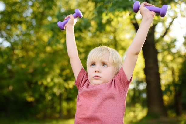 istock Cute little boy lifting dumbbells outdoors 1081626408
