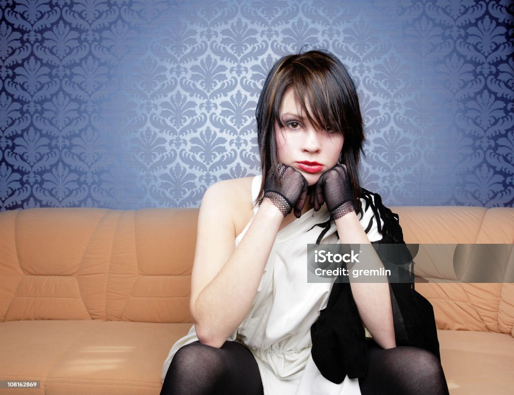 Ritratto di giovane donna seduta su un divano - Foto stock royalty-free di Abbigliamento casual