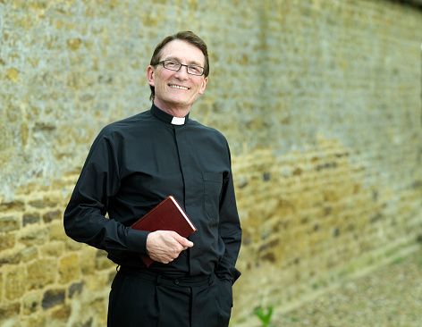 Close up portrait of white haired senior priest looking at camera with smile, copy space