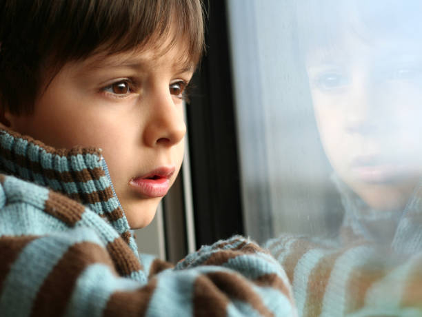 istock Little Boy Looking out of a Window 108162919