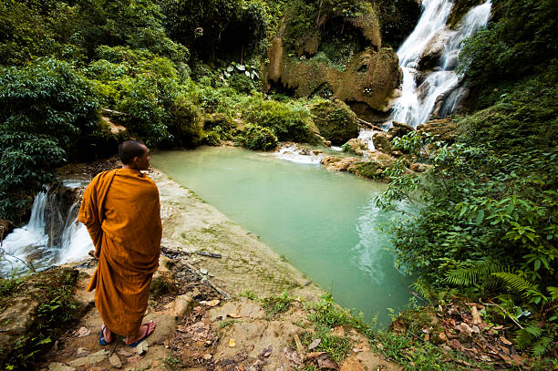 Monk Viewing Tat Kuang Si Waterfall in Laos stock photo