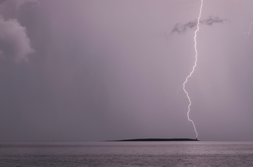 Night shot of a lightning hitting a lighthouse on a smal