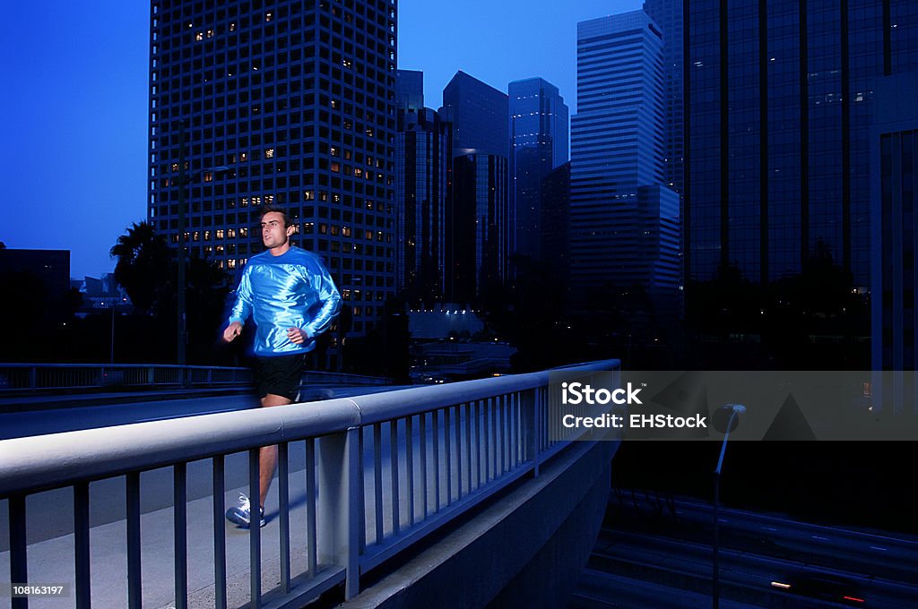 Athlétique jeune homme jogging sur le pont au coucher du soleil - Photo de Adulte libre de droits