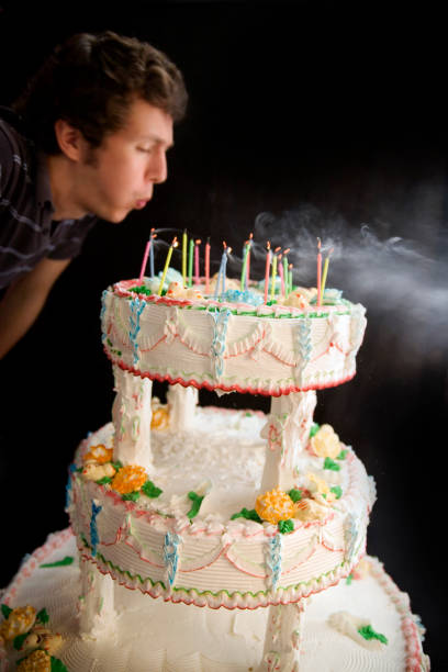 istock Man Blowing Out Candles on Tiered Cake 108163228
