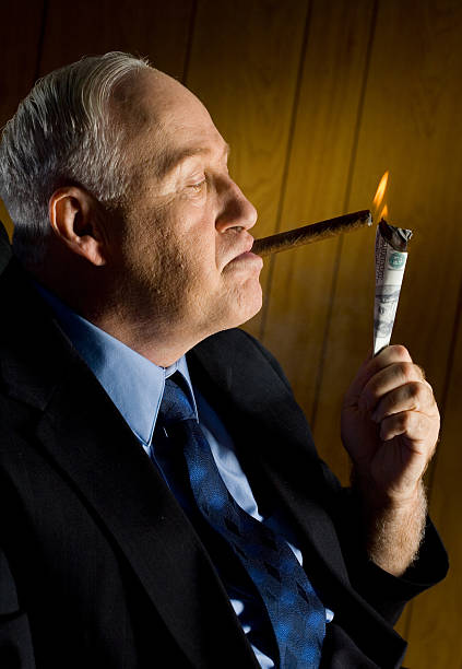 Man lighting cigar with 100 Dollar Bill stock photo