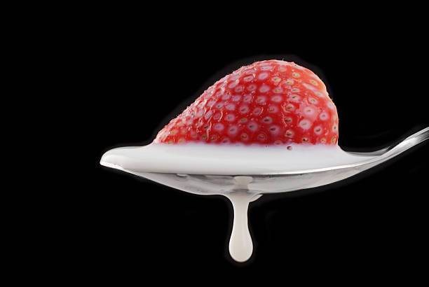 Milk Dripping from spoon with Strawberry. stock photo