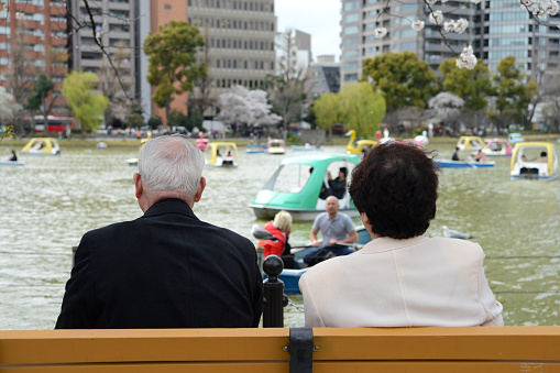 Tokyo, Japan - April 2, 2014:The old couple who watchs the lake sitting on the bench in ueno park