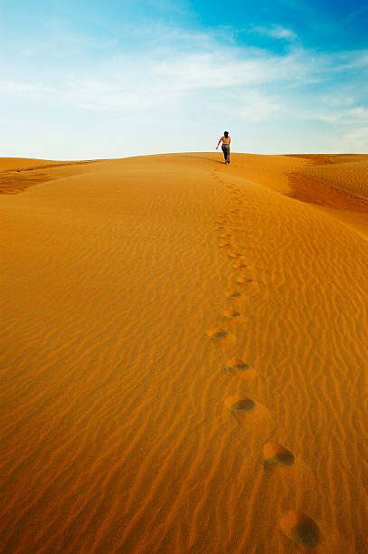 istock Woman Leaving Footprints and Going Up Desert Sand Dune 108163398