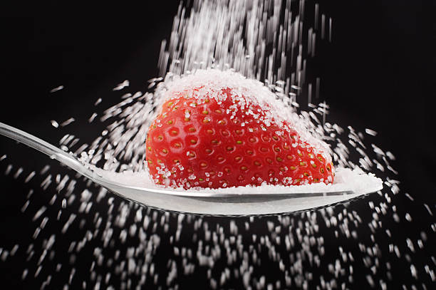Pouring Sugar onto Strawberry on Spoon stock photo
