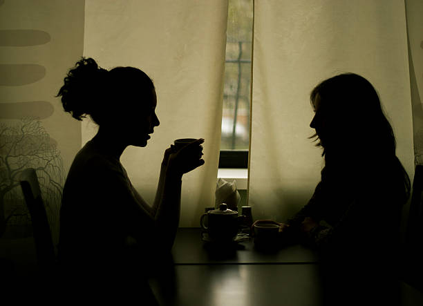 シルエットの 2 人の女性が飲むティーのカフェ - whispering women talking mystery ストックフォトと画像