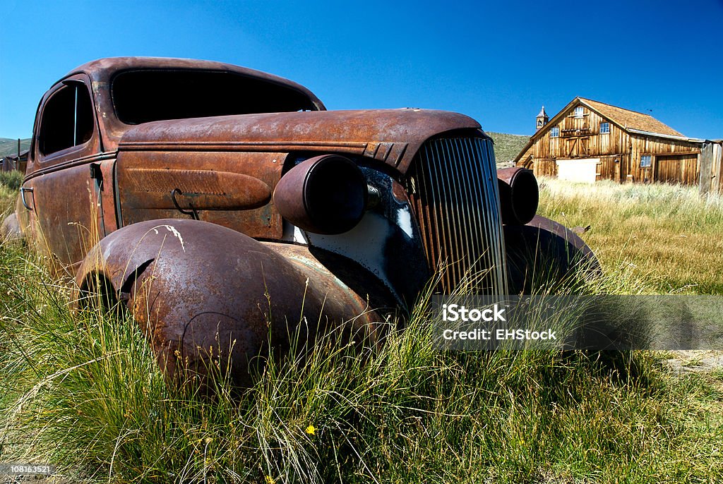 Carro enferrujado num campo com um celeiro cidade fantasma de Bodie Califórnia - Foto de stock de Carro royalty-free