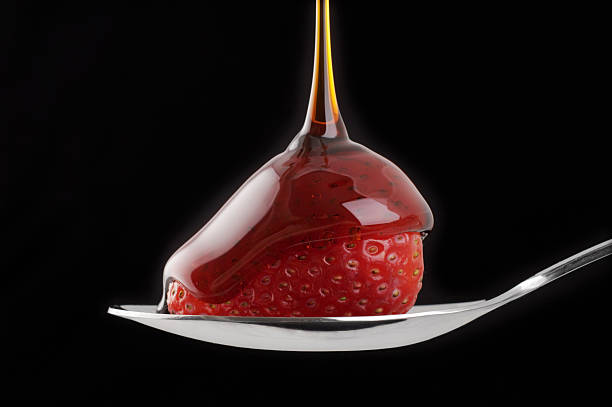 Pouring Syrup Over Strawberry on Spoon stock photo