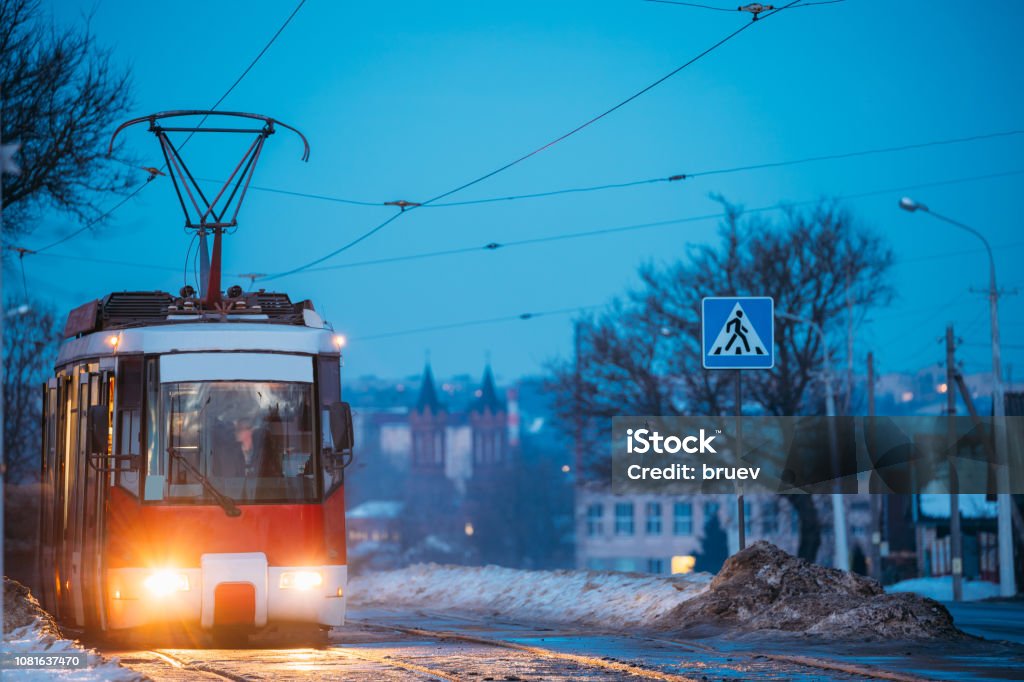 Vitebsk, Belarus. Public Old Retro Tram Of Route Number Eight Moving Near Private Sector And Old Cathedral Of St. Barbara In Evening Night Illuminations At Winter Vitebsk, Belarus. Public Old Retro Tram Of Route Number Eight Moving Near Private Sector And Old Cathedral Of St. Barbara In Evening Night Illuminations At Winter. Rail Transportation Stock Photo