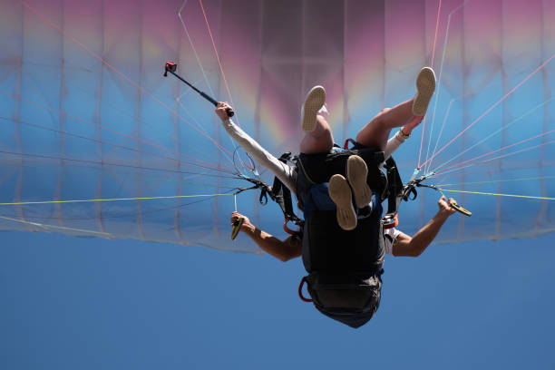 Real people, actual young couple doing tandem paragliding. Slight motion blur due to relative speed.
