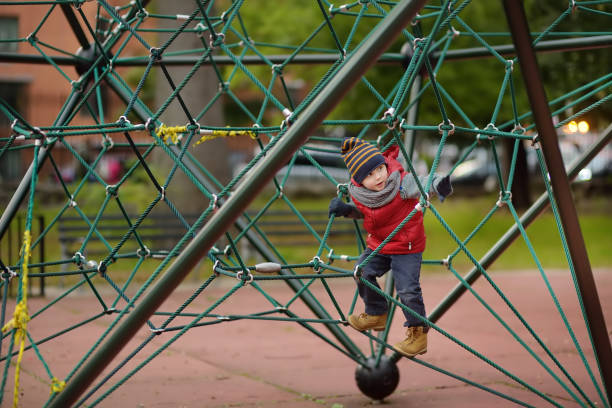 Little boy playing on modern kids play ground.Outdoor activity for kids in autumn/spring.