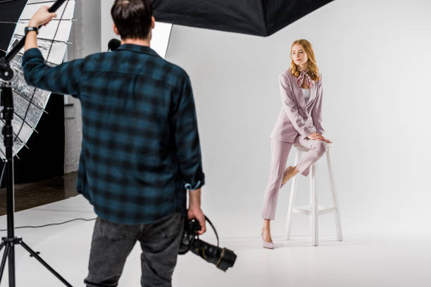 istock back view of photographer holding camera and model posing in studio 1081643796