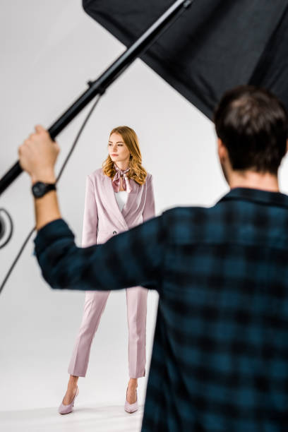 istock back view of photographer working with lighting equipment while female model posing in studio 1081643808