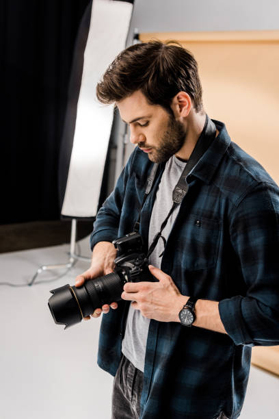 istock handsome young photographer using camera in photo studio 1081643944