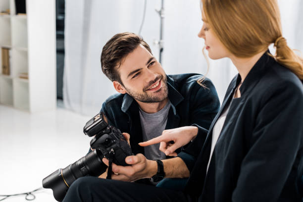istock happy young photographer and model using photo camera together in studio 1081644054