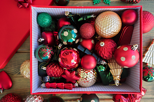 Red Box filled with New Year decorations on wooden background.