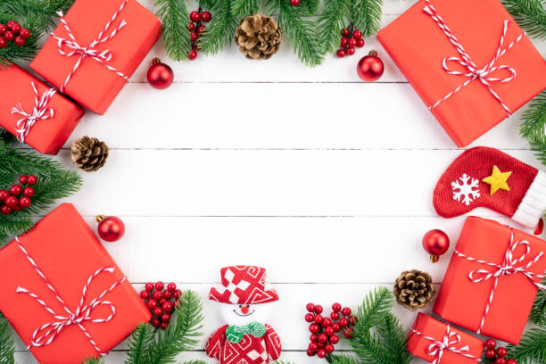istock Christmas background concept. Top view of Christmas red gift box with spruce branches, pine cones, red berries and bell on white wooden background. 1081668152