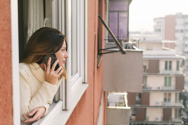 istock Young woman talking on mobile phone by the window on daylight 1081674450