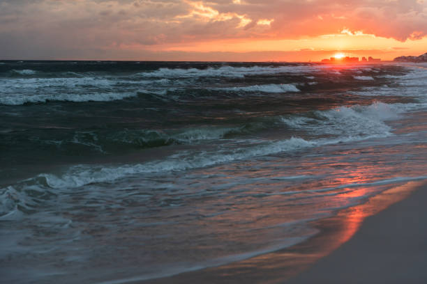 Red orange, dramatic sunset in Santa Rosa Beach, Florida with coastline coast in panhandle with ocean gulf mexico waves, dark, nobody