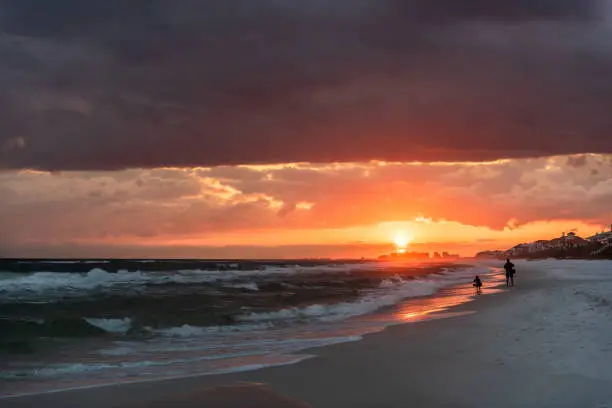 Red, yellow, orange, dramatic sunset in Santa Rosa Beach, Florida with coastline coast in panhandle with ocean gulf mexico waves, hurricane storm