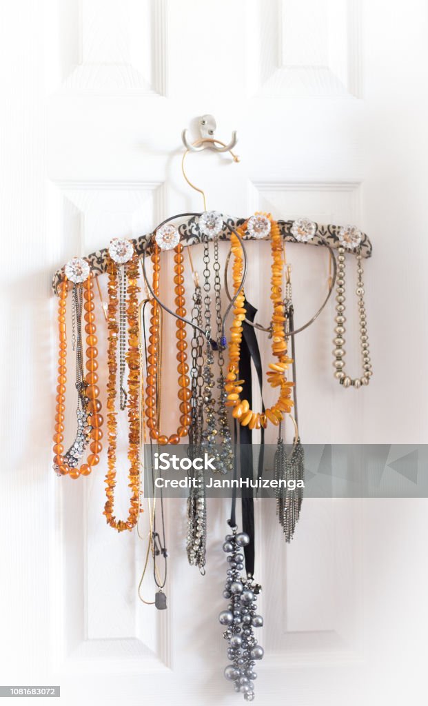 Amber Necklaces Organized On Fancy Hanger Amber necklaces organized and hanging from a fancy hanger on the back of a white door. Hanging Stock Photo