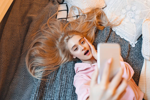istock Surprised young girl, making selfie with smart phone while lying 1081686116