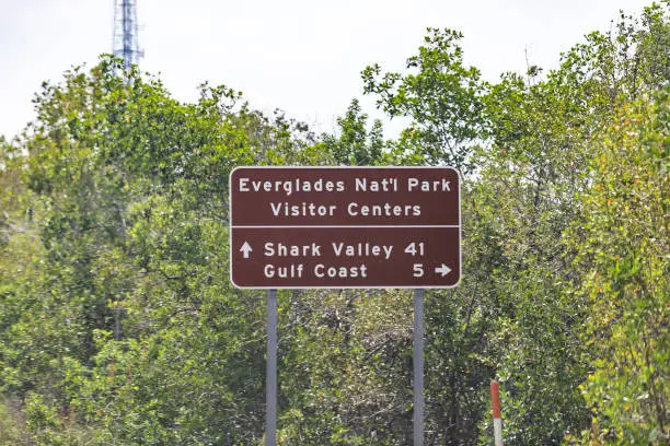Sign for Everglades National Park Visitor Center and Shark Valley Gulf Coast in Florida street road highway, green trees