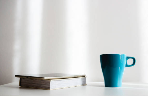 istock Tablet, paper book and cup in light cozy interior 1081688604