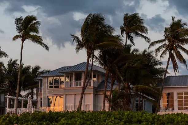 Photo of Coast house beachfront waterfront vacation home, house during evening sunset with nobody in Florida, gulf of mexico, storm weather and wind palm trees