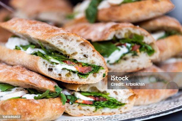 Closeup Of Fresh Display Of Stacked Pile Of Panini Bread Mozzarella Melted Cheese Vegetarian Italian Tomatoes Basil Lettuce In Store Shop Cafe Buffet Catering Sandwiches Stock Photo - Download Image Now