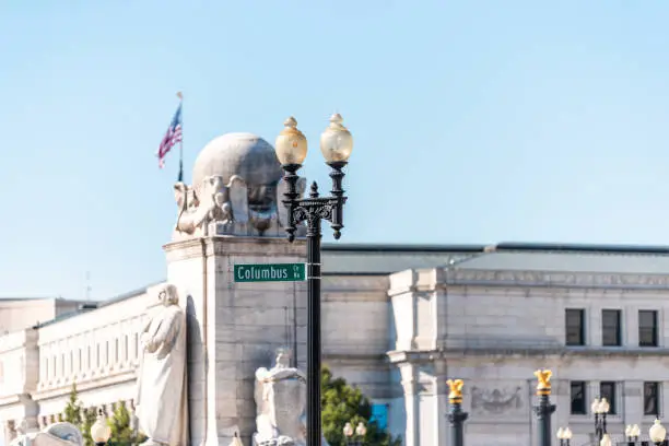 Washington DC, USA Union Station with Columbus Circle street sign, road, entrance exterior facade, American Flag