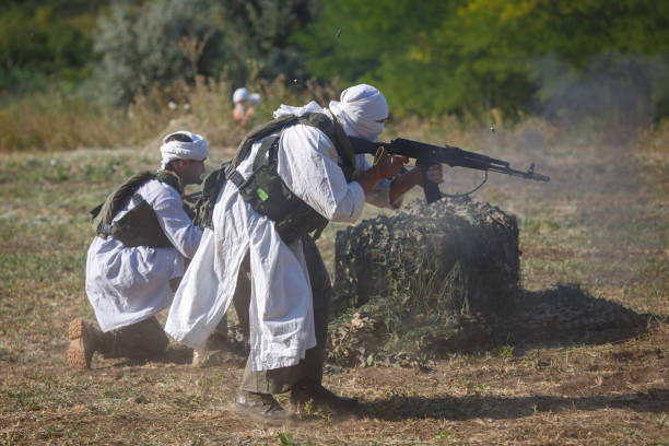 two mujahideen shoot from behind intrenchment - jihad imagens e fotografias de stock