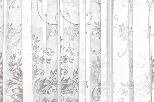 Closeup of lace white window curtains blinds in bright room interior indoors with floral pattern design abstract decoration